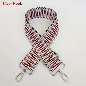 Detail of adjustable woven purse strap with silver hooks and red geometric embroidery pattern