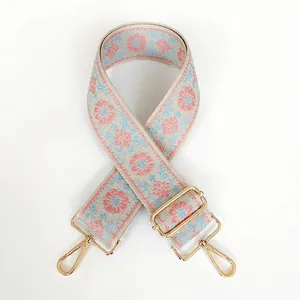 Détail de la sangle tissée florale beige et rose avec mousquetons en métal doré