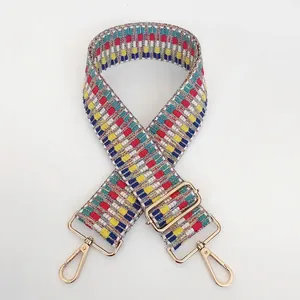 Close-up of adjustable woven purse strap with colorful geometric embroidery and gold hardware