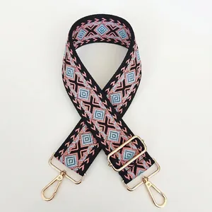 Close-up of thick canvas bag strap with pink geometric jacquard pattern and gold metal hooks