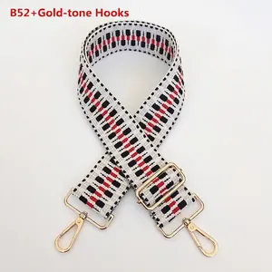 Detail of adjustable woven handbag strap with red geometric pattern and gold metal hooks
