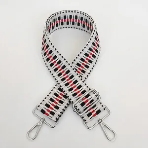 Detail view of woven ethnic shoulder strap with black, white, red pattern and silver hooks
