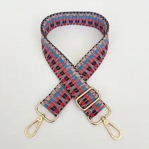 Macro detail of adjustable woven bag strap with geometric patterns and gold metal hooks