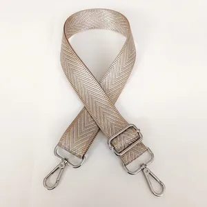 Detail of adjustable khaki woven strap with silver chevron pattern and metal hooks
