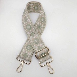 Détail d'une bandoulière tissée bohème avec mousquetons et boucles en métal doré