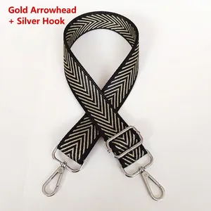 Detail of adjustable black and gold arrow pattern bag strap with silver metal hooks