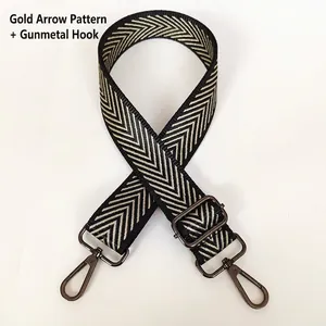 Detail of adjustable wide shoulder strap with gold arrow pattern and gunmetal swivel hooks