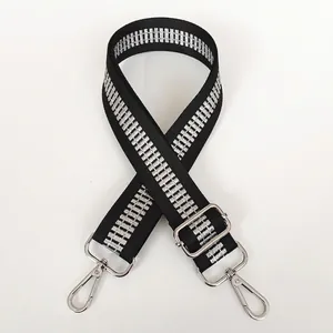Close-up of black crossbody bag strap with silver geometric pattern and metal hooks