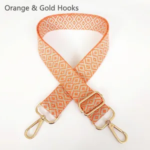 Detail of adjustable orange geometric jacquard canvas strap with golden metal carabiner hooks