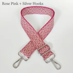 Detail of rose pink and beige geometric jacquard canvas bag strap with silver metal hooks