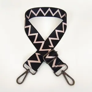 Macro view of adjustable pink and black geometric pattern wide shoulder strap with metal hooks