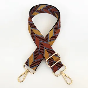 Detail of adjustable geometric canvas bag strap with golden metal hooks and buckles