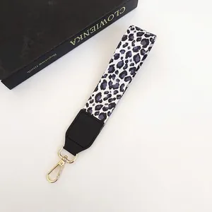 Détail de la dragonne imprimé léopard avec cuir noir et crochet rotatif en métal doré