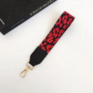 Détail de la lanière léopard rouge et noire avec cuir noir et crochet doré