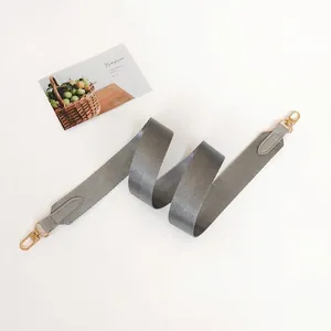 Detail of grey fabric replacement strap with gold metal hooks and leather reinforced ends