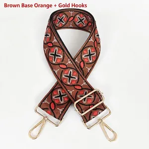 Detail of bohemian geometric woven wide bag strap in brown and orange with gold metal hooks