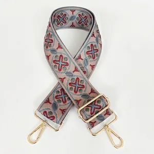 Close-up of geometric jacquard woven strap with pink base and gold metal snap hooks