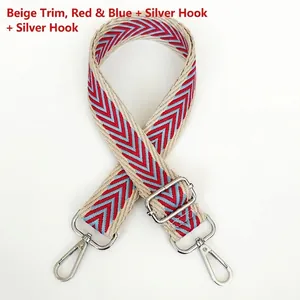 Close-up of beige woven bag strap with red and blue zigzag pattern and silver metal hooks