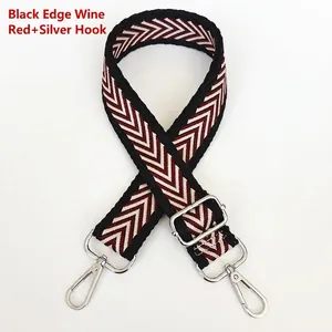 Detail of wide canvas bag strap with burgundy V-shape pattern and silver metal hooks