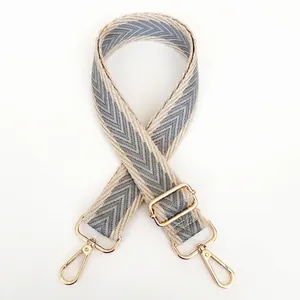Detail of adjustable canvas strap with grey herringbone pattern and gold metal clasp