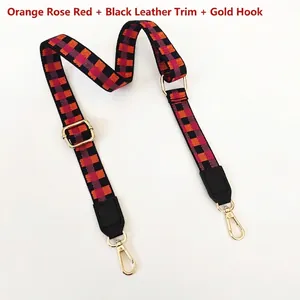 Détail de la bandoulière tissée à carreaux orange, magenta et noire avec crochets dorés