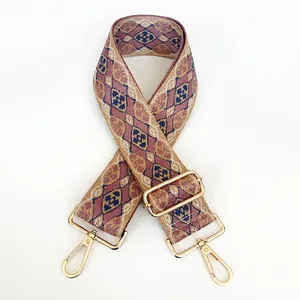 Close-up of wide jacquard strap with geometric pattern and gold swivel snap hooks