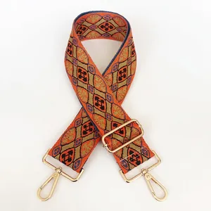 Detail of colorful geometric embroidery on a wide bag strap with gold metal hooks
