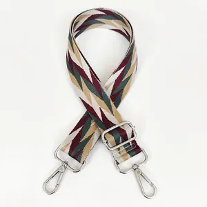 Detail view of woven geometric bag strap with silver metal hooks and adjustable buckle