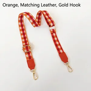 Détail de la bandoulière tressée à carreaux avec cuir orange et crochets dorés