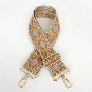 Detail of embroidered geometric crossbody strap with gold metal buckles and lobster clasps
