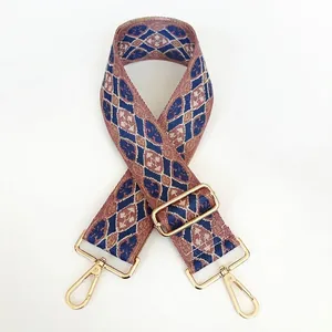 Detail of embroidered geometric bag strap with vintage pattern and gold metal hooks