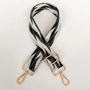 Detailed view of woven canvas bag strap with geometric wave pattern and gold metal hooks