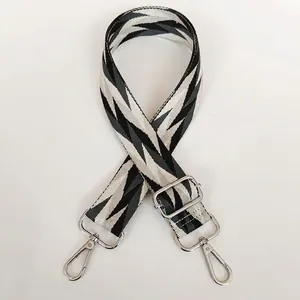 Detail of adjustable woven shoulder strap with black and white zigzag pattern and silver hooks
