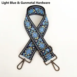 Detail of light blue ethnic embroidered bag strap with floral patterns and gold hooks