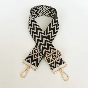 Detail of black and cream zigzag woven strap with shiny gold metal hooks and buckle