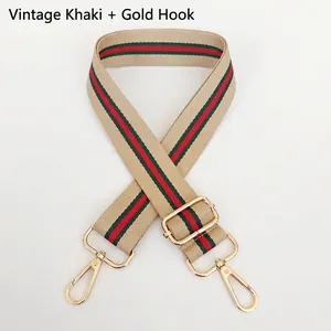 Detail of vintage khaki canvas bag strap with red and green stripes and gold hooks