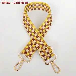 Détail d'une large bandoulière réglable à damier avec des mousquetons dorés chic