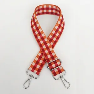 Vue détaillée d'une bandoulière tissée ajustable à carreaux orange et rouge et boucles argent