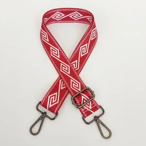 Detail of red nylon bag strap with white geometric pattern and silver metal hooks
