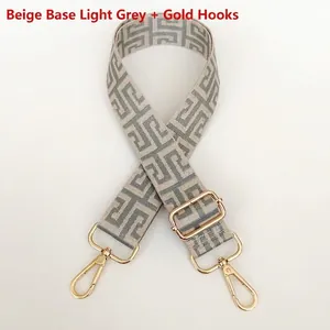 Detail view of woven beige and grey Greek key pattern bag strap with gold metal hooks