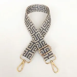 Detail of adjustable off-white and grey geometric canvas bag strap with gold metal hooks
