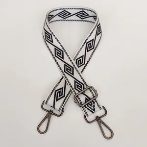 Close-up of off-white wide bag strap with geometric pattern and gunmetal metal hooks