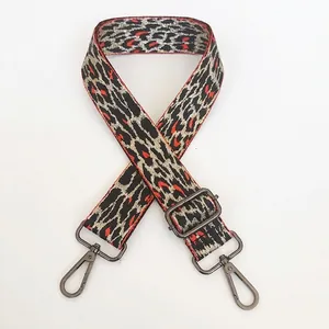 Detail of adjustable leopard print bag strap with orange accents and gunmetal hooks