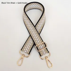 Detail of khaki canvas bag strap with white dots, black edges and gold metal hooks