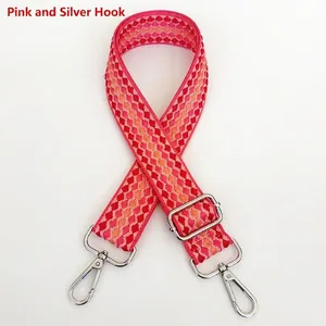 Detail of woven plaid purse strap in pink and red with silver metal swivel hooks
