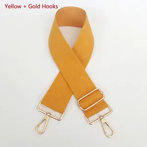 Detail view of yellow woven canvas bag strap with golden metal lobster clasps and buckle