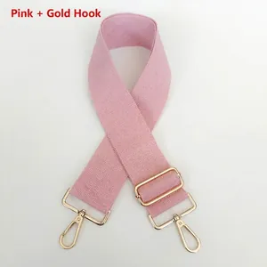 Detail of adjustable pink canvas bag strap with durable gold metal swivel hooks and buckles