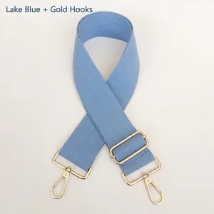 Detail of lake blue wide woven canvas bag strap with adjustable gold metal buckle