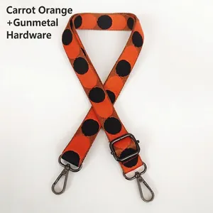Close-up of adjustable polka dot bag strap with gunmetal clasps in carrot orange color
