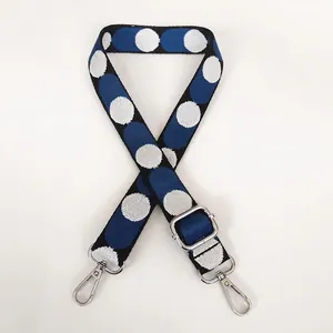 Close-up of adjustable woven shoulder strap with blue and white polka dots and silver hooks